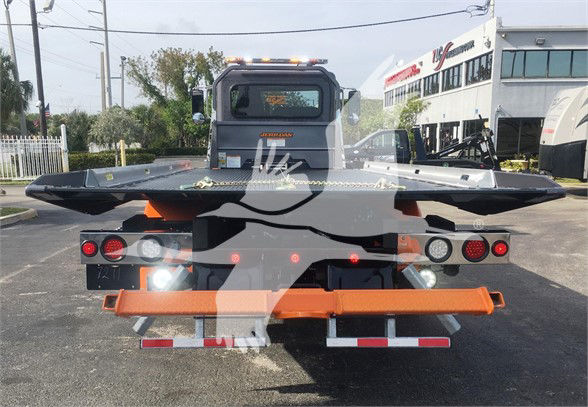 Peterbilt 337 tow truck rear view with specialized flatbed equipment and orange rear bumper.