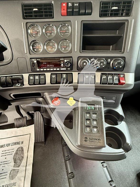 Kenworth T880 cab dashboard showing instrument gauges, radio, climate controls, and a gear selector with Allison transmission shifter.