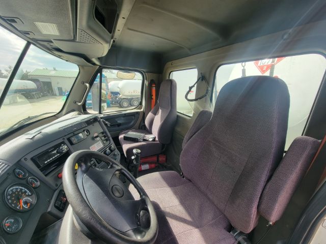 Cab interior of a 2016 Freightliner Cascadia showing steering wheel, dashboard, and two front seats.