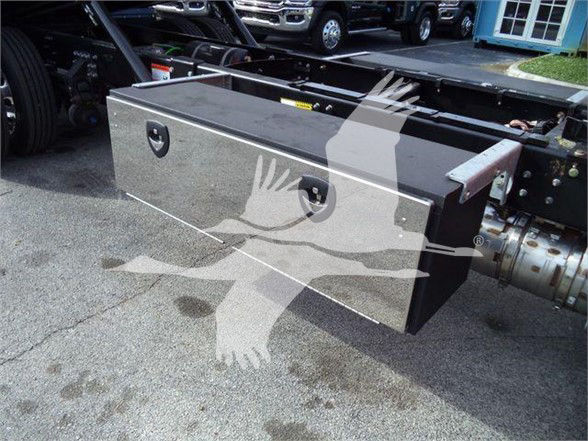Mack MD6 truck chassis showing a rectangular aluminum toolbox mounted near the cab with handles on the front face and hydraulic lines nearby.