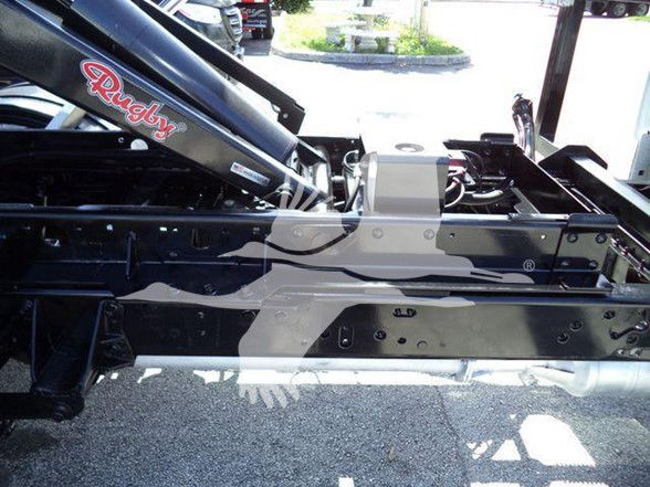 Ford F-550 chassis frame with Rugby hydraulic component visible, stock number T04065FM in background.