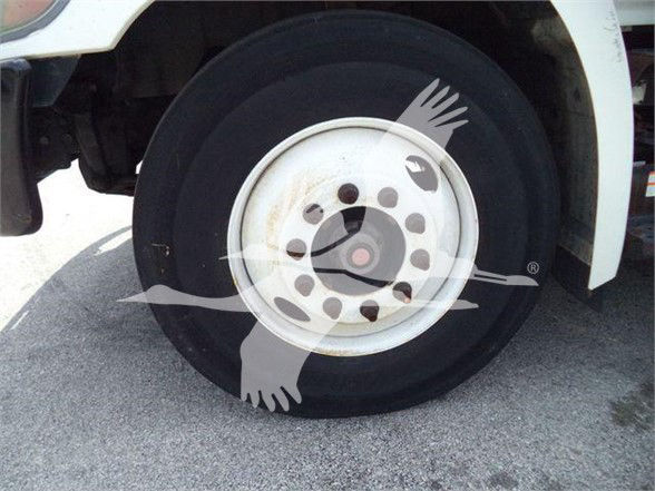 Truck front wheel showing white steel rim and black tire in a reefer truck with stock number 200151R.