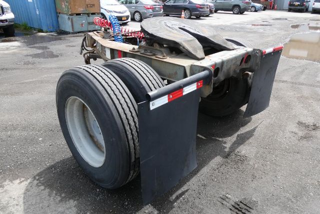 Dolly trailer rear view showing dual wheels and fenders with reflective strips; Fruehauf ELFI trailer in lot.