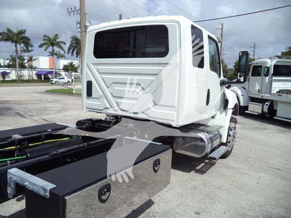 Tow truck chassis rear cab area showing flatbed mounting and fuel tank, white cab, black metal toolbox along chassis.