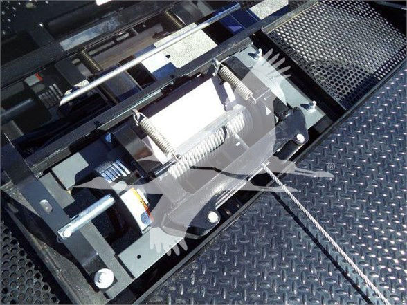 Ford F750 SD truck bed winch assembly with hydraulic lines and metal grid surface.