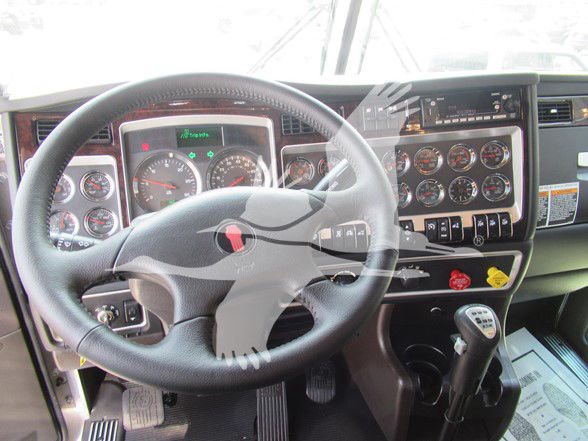 Kenworth W900L truck interior showing steering wheel, dashboard with multiple gauges, and gear shifter.