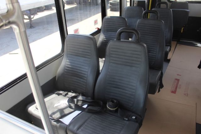 Ford E-450 shuttle bus interior showing front and middle rows of gray, vinyl seats with seat belts and large windows.