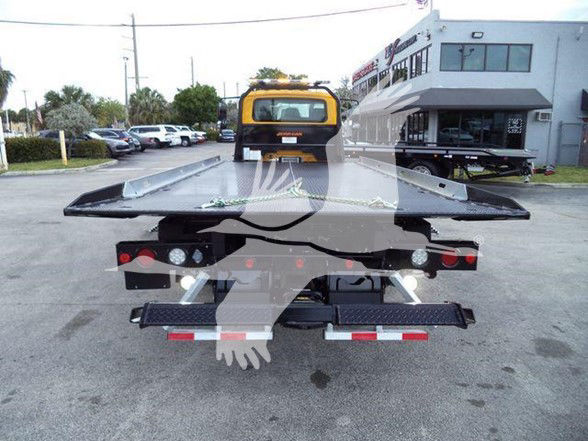 Tow truck flatbed rear view with hauler equipment and lights visible.