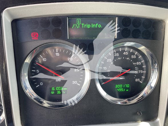 Kenworth T800 instrument cluster showing tachometer and speedometer with digital readouts. Left gauge shows RPM up to 30, green trip data at bottom; right gauge shows speed up to 75 mph with odometer and trip info in green.