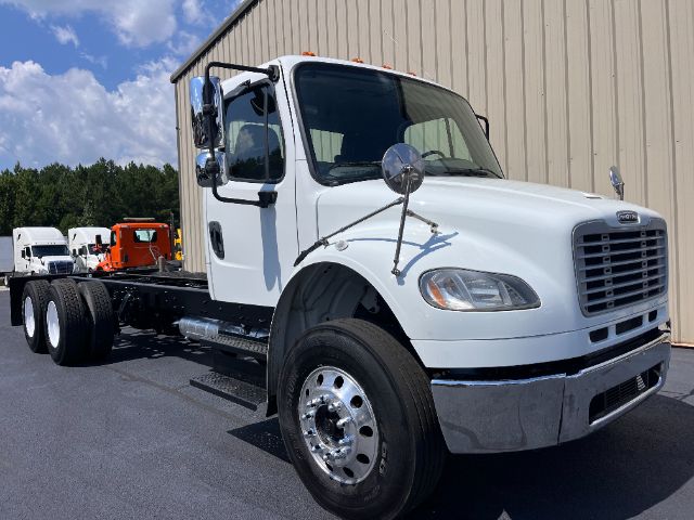 2015 Freightliner M2 cab and chassis truck showing front grille, white cab, dual mirrors, large front bumper, and chassis with dual rear axles.