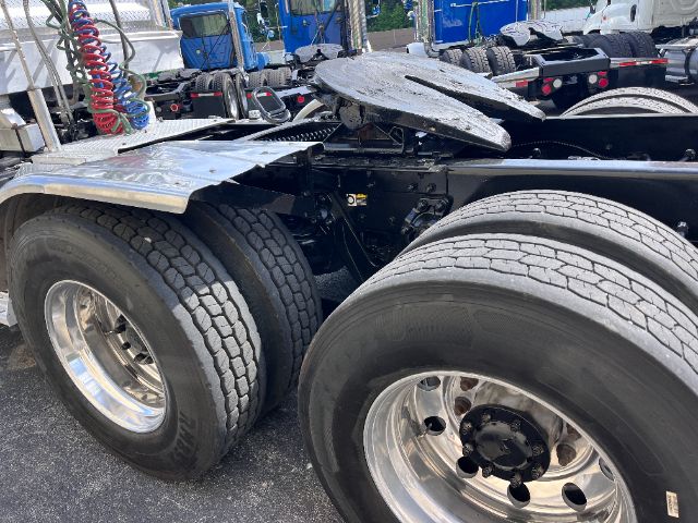 Kenworth T800 tractor mid-section showing dual rear axles and wheel cluster with metal fifth wheel and air lines.