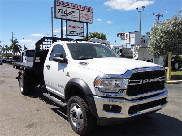 2024 Ram 5500 HD truck with hooklift bed in a dealership lot, front grille showing RAM emblem, side mirrors, and dual rear wheels.