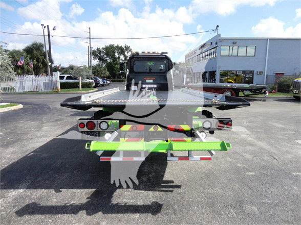Rear view of a 2022 Peterbilt 337 tow truck with a green and black wheel-lift, and various tail lights. Visible text includes 'PETERBILT' on the cab rear window area and some stickers on the rear equipment.