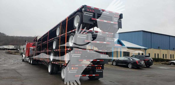 Truck trailer with black and red stripes, multiple wheels, Transcraft logo visible.
