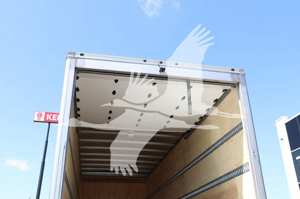 Open cargo box of a 2025 Hino L6 cab and chassis truck with stock HI1849; interior wood panels; overhead rails; blue sky.