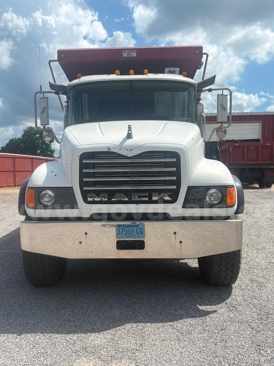 Mack CV713 dump truck front view showing grille, headlights, bumper, and Alabama license plate.