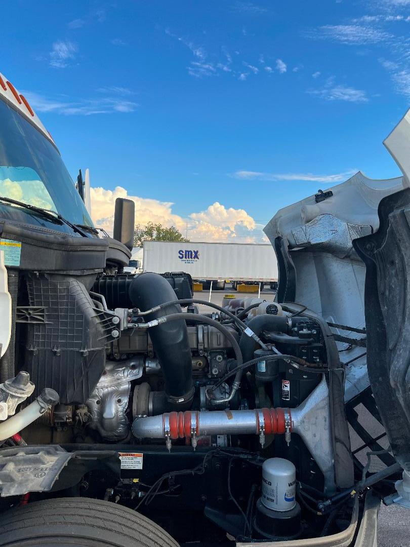 Truck engine bay of a 2021 Freightliner Cascadia 126 showing intake hoses, radiator, and front engine components.
