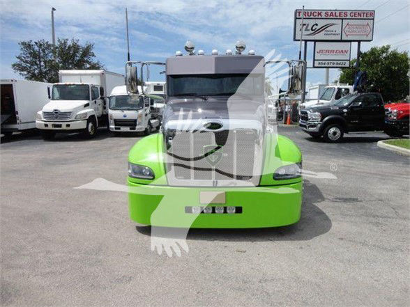 Front view of a bright green 2020 Peterbilt 337 tractor with chrome grille, large windshield, and air intake; trucks in background at a dealership lot.