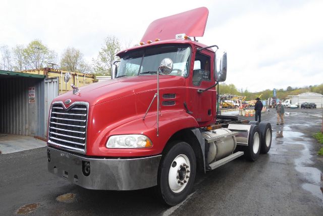 Cabbage red 2007 Mack CXN613 conventional daycab truck showing front grille and cab with open hood.