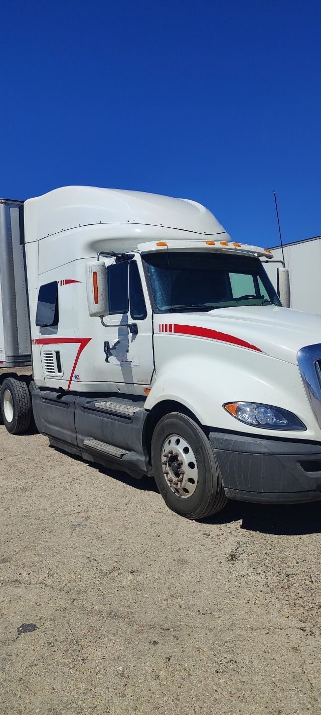 White 2016 International ProStar semi-truck with aerodynamic sleeper cab, side red stripe decals, large black front bumper, and dual rear wheels.