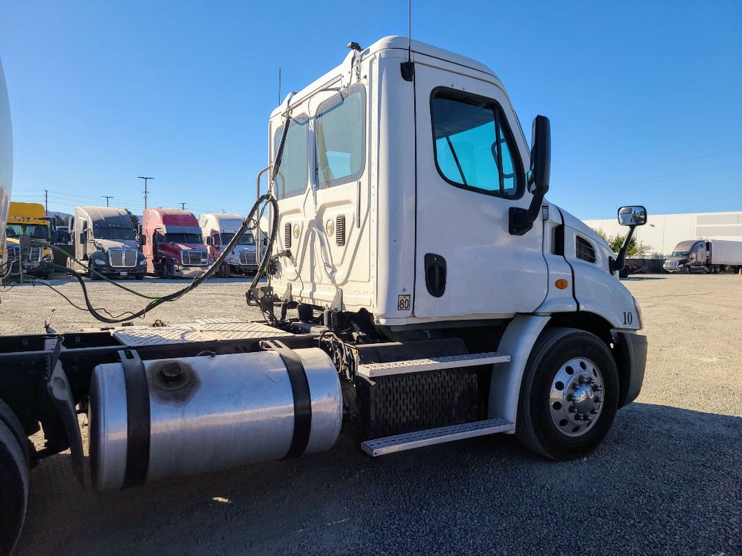 Truck cab side view with white Freightliner Cascadia 113, fuel tank, steps, and side mirrors visible.