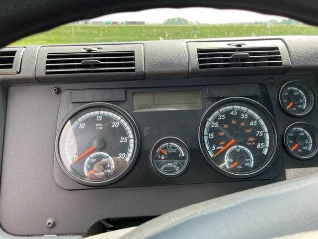 Dashboard of a Freightliner Cascadia truck showing gauges and digital display. Visible text includes tachometer numbers, speedometer, and small gauges.
