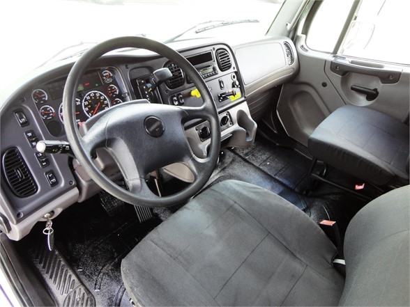 Freightliner Business Class M2 106 truck interior showing steering wheel, dashboard gauges, and front seats.