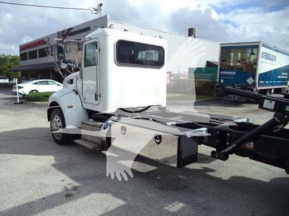 Front-left view of a white 2019 Peterbilt 337 tow truck chassis with cab, fuel/tool boxes, and hitch ready for a truck bed.