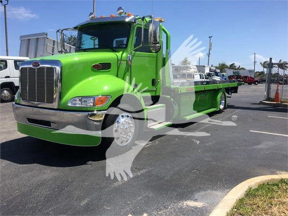 Green 2022 Peterbilt 337 tow truck in a dealership lot with stock number J52310