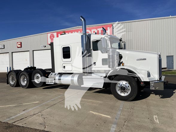 Kenworth T800 conventional sleeper truck in white, side view showing cab with tall exhaust stacks, triple rear axles, and chrome fuel tanks.