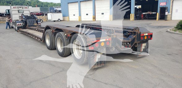 Fontaine 55 Ton lowboy trailer with drop-side rails, three rear axles, and mud flaps; visible stock number plate and rear lights.