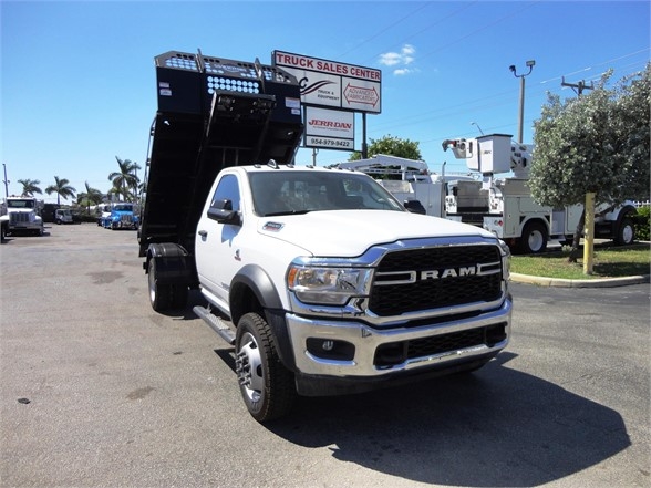 Ram 5500 HD dump truck with hooklift bed in white, front three-quarter view.
