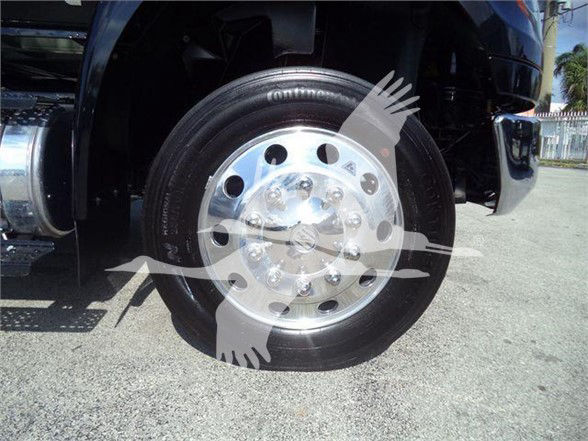 Wheel and tire on a heavy-duty truck front axle with chrome hub and lug nuts visible.