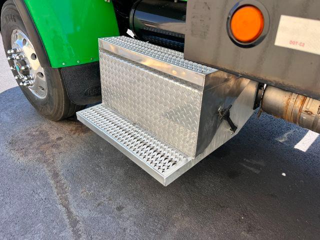 Aluminum diamond plate side toolbox under a Peterbilt 348 with green cab and step-down side step.