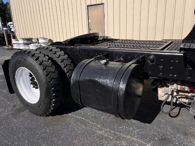 Rear side view of a Kalmar Ottawa 30 yard truck chassis showing a large round black fuel/tank or accumulator under the frame and dual rear tires.