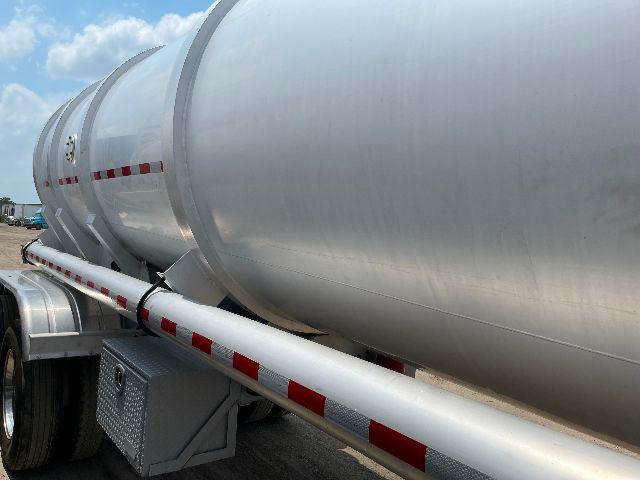 Crude oil tanker trailer showing aluminum DOT407 tank with red and white reflective strips along the side and support piping.