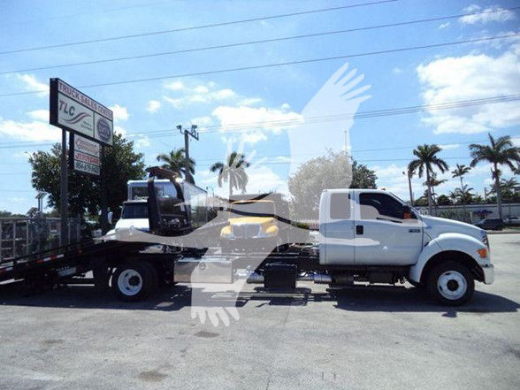 2015 Ford F650 XLT tow truck side view showing flatbed with white cab and black chassis.