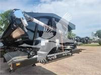 Dump trailer with hydraulic tilt bed and detachable hopper visible in a yard, showing a black/gray metal frame and landing gear. Text on image includes signage/watermark but is not legible.