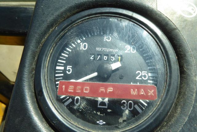 Gauge cluster with an orange-red label reading 1250 FP MAX and numbers around 0-30, showing a speedometer-style tachometer in a Massey Ferguson backhoe context.