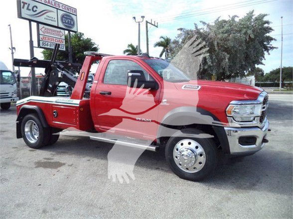 Red 2024 Ram 4500 SLT tow truck with boom in a dealership lot, side view showing front chrome bumper and dual rear wheels.