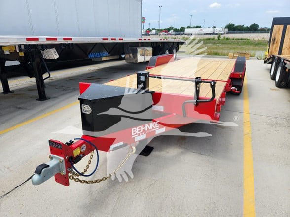 Behnke flatbed trailer in a parking lot showing front hitch with safety chain and wooden deck.