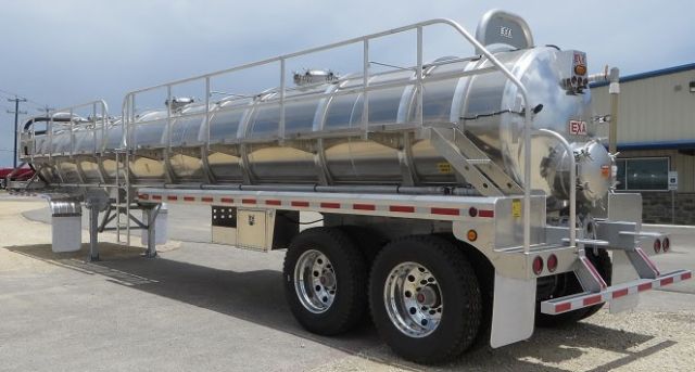 EXA aluminum vacuum tank trailer, dual rear axles, cylindrical polished aluminum tank with ladder and railing, rear bumper with lights and EXA logo.