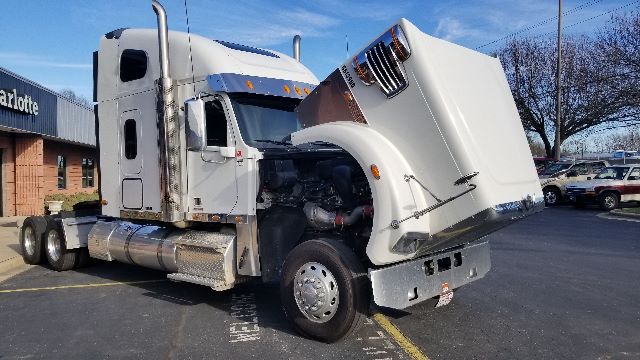 2013 Freightliner Coronado 132 truck with hood open showing engine bay and chrome fuel tanks; tandem rear axles visible.