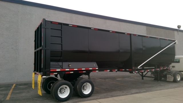 Great Dane dump trailer with 40 ft round-bottom design, black body, dual rear axles, side ladder, and reflective tape.