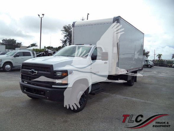 2023 Chevrolet Silverado 6500HD box truck with a large box body, front grille featuring Chevrolet bowtie, in a dealership lot.
