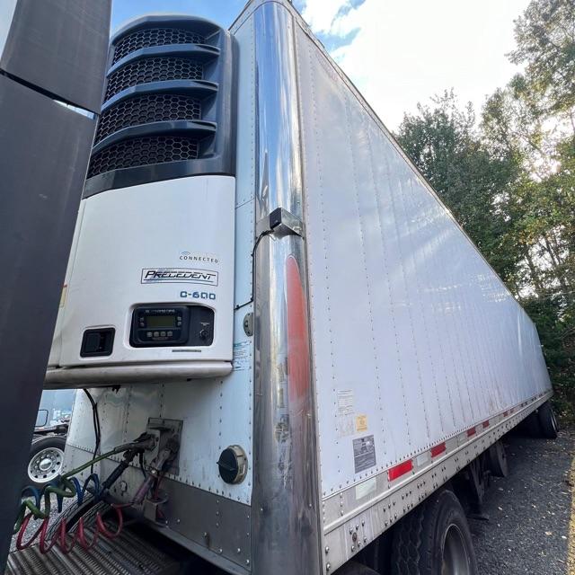 Trailer front left corner showing a C-600 Precedent refrigerated unit on a Wabash Arctic Lite trailer with an open refrigeration unit and attached hoses.
