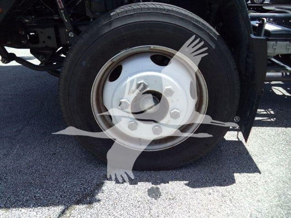 Isuzu truck wheel and tire visible on a dump truck chassis with a white wheel cover. No labels readable on the visible portion.