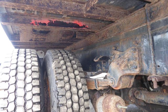 Freightliner M2 106 undercarriage showing twin rear wheels, suspension, and frame with visible rust and structural components.