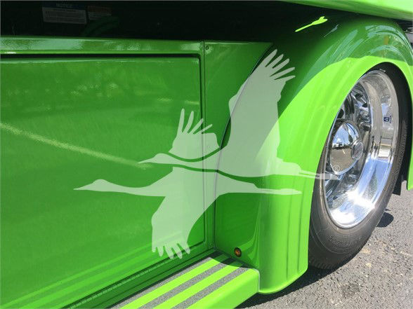 Tractor truck body panel and chrome wheel of a bright green 2022 Peterbilt 337 tow truck showing glossy finish and reflection.