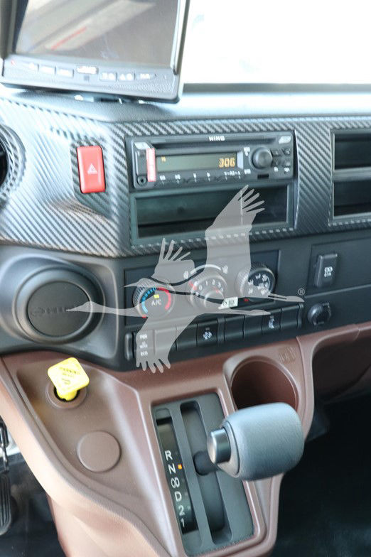 Cab interior showing center stack with radio, climate controls, and gear selector. Visible text includes UNK model details on radio and climate control dials.